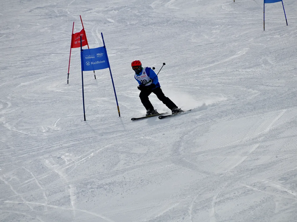 Skifahrer in tiefer Hocke zwischen zwei Toren.